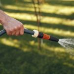 Man watering his plants in his garden. Man in a blue shirt.